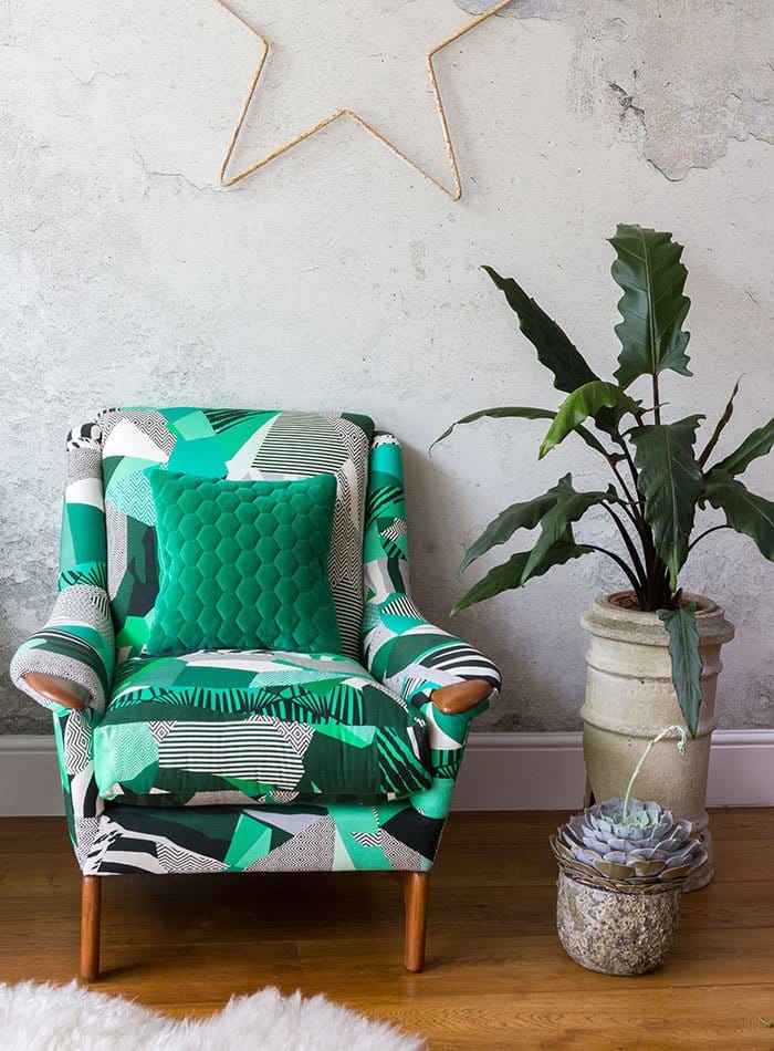 Reupholstered green patterned armchair against concrete background