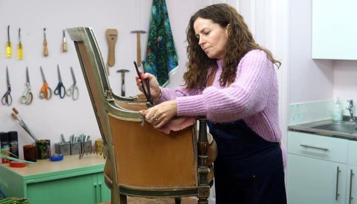 Sharon O'Connor reupholstering an armchair in workshop