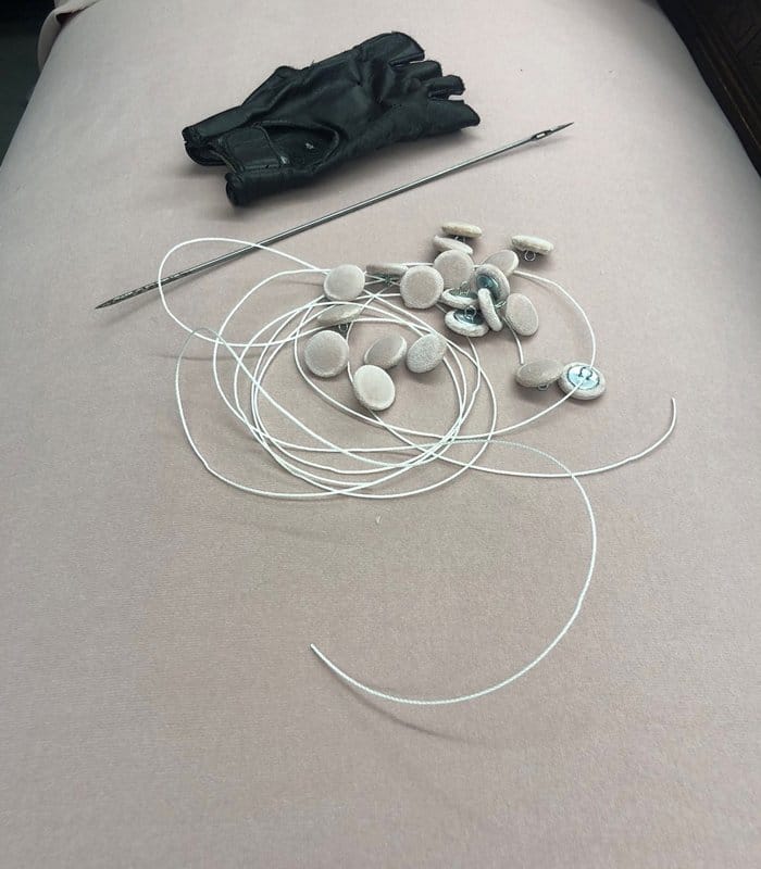 Upholstery supplies including buttons with thread and needle