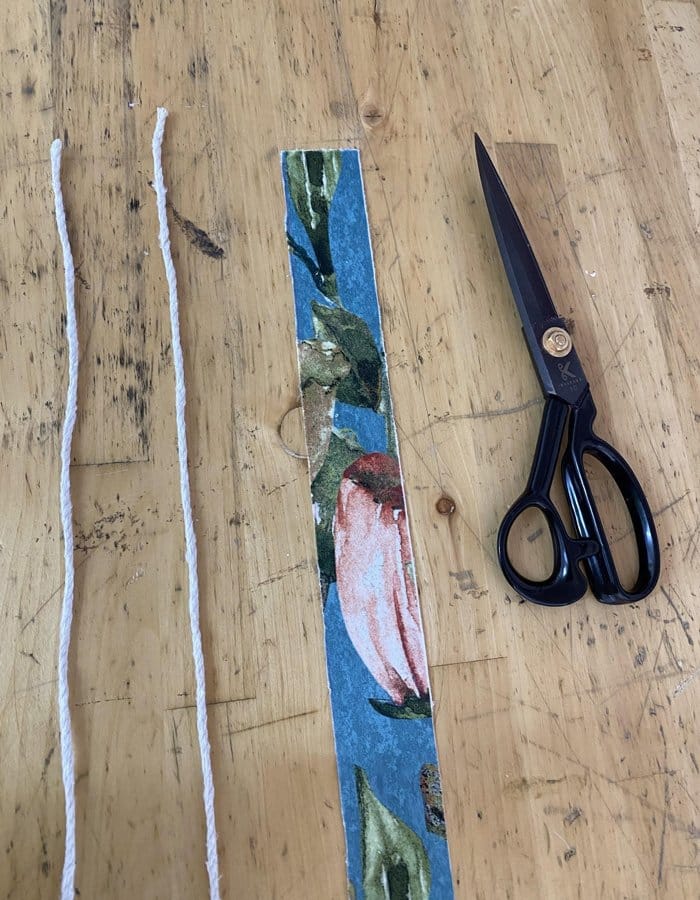 Scissors with two lines of string and strip of fabric which is used for double piping upholstery