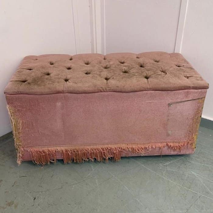 an old, pink fabric ottoman prior to being upholstered