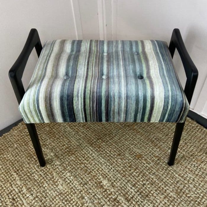 an upholstered dressing table stool with a striped pattern
