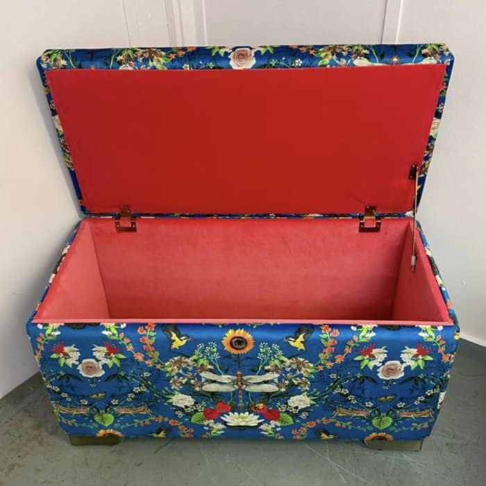 an upholstered ottoman with its lid open showing a pink interior