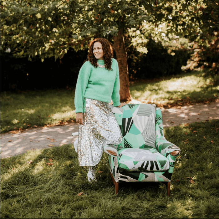 Sharon O Connor upholsterer stood beneath a tree alongside a recent chair reupholstery project