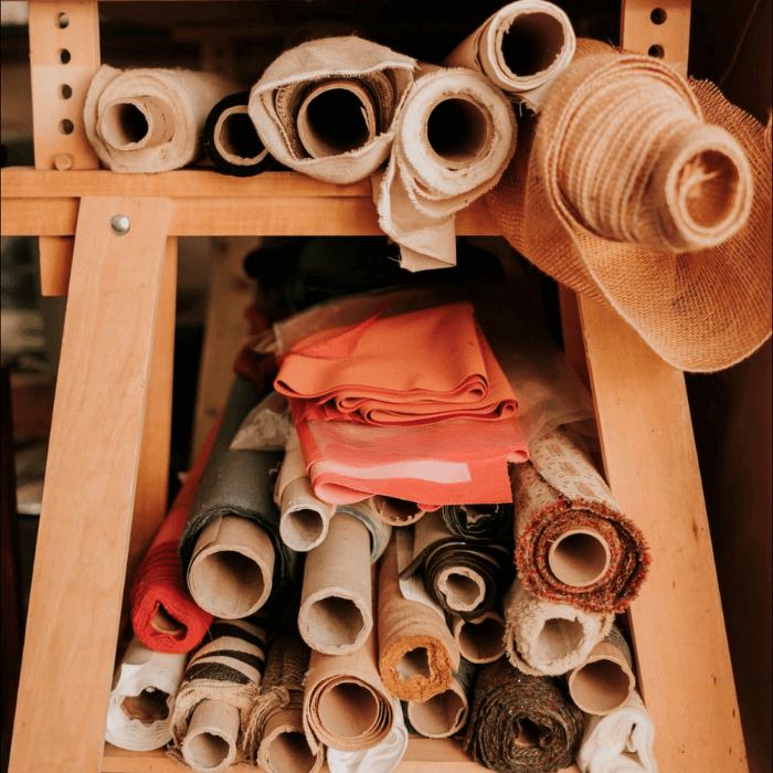 Rolls of fabric sit under a workbench in the Vintique Upholstery studio