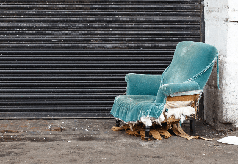 A  blue velvet chair, abandoned in front of a warehouse.