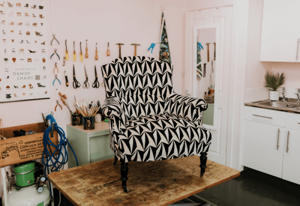 A completed upholstery project sits atop a workbench in the Vintique Upholstery workshop.
