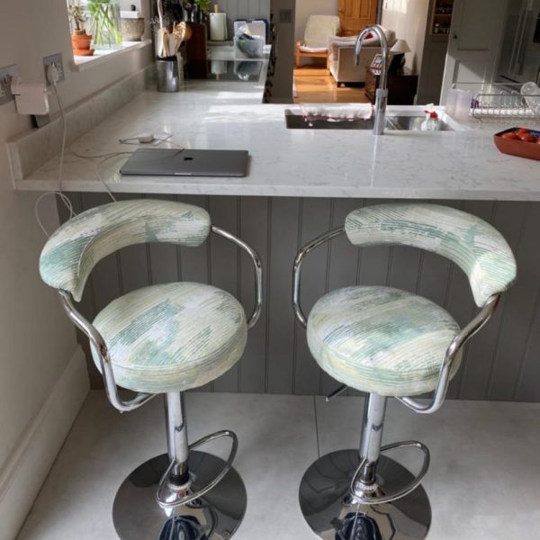2 reupholstered kitchen bar stools with metal base and covered in neutral fabric