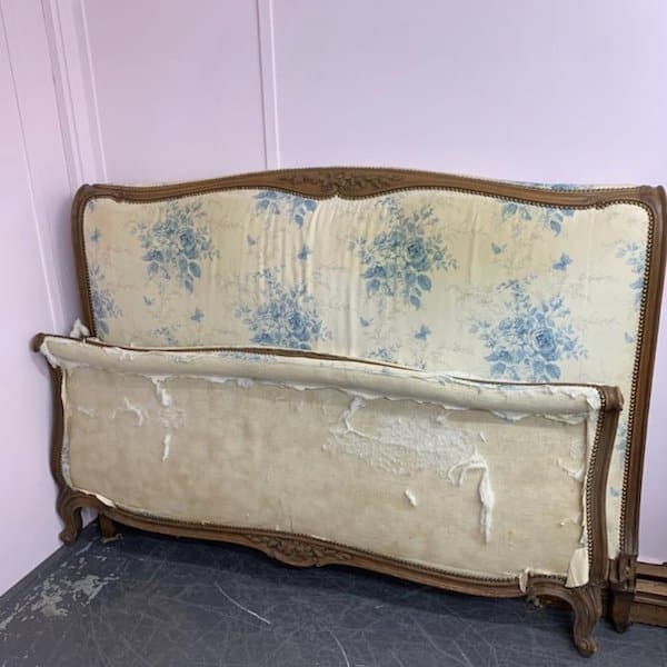 Antique bed frame wiith ripped fabric, in need of reupholstery