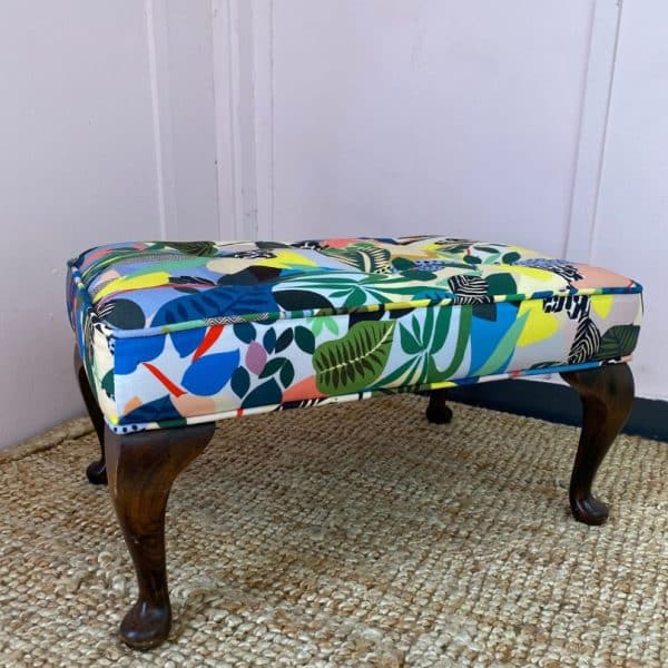 Footstool with dark wooden legs and a bold and bright fabric top