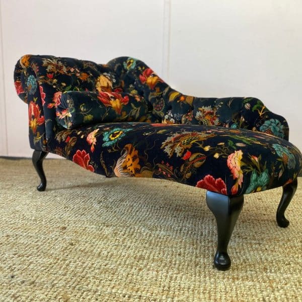 Chaise longue in dark velvet with a bright floral pattern and dark wooden legs