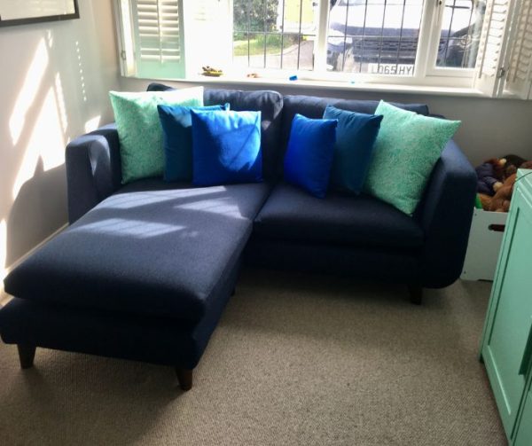 L shaped modern sofa reupholstered in navy blue with assorted blue and green cushions