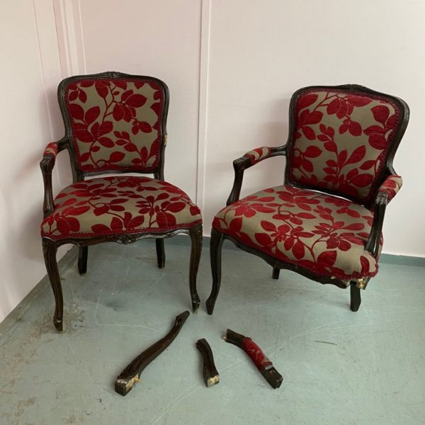 Pair of damaged chairs in need of reupholstery with red printed fabric