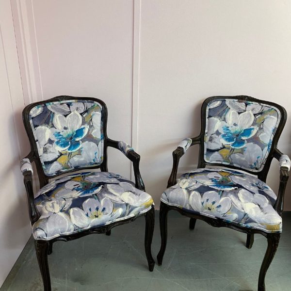 Pair of reupholstered chairs in a floral, watercolour pattern with dark wood legs and arms