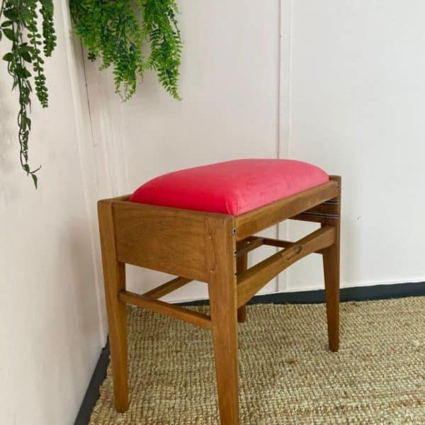 Wooden piano stool with red fabric seat awaiting reupholstery