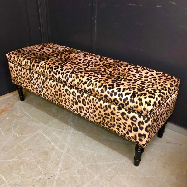 Reupholstered ottoman with leopard fabric, buttons and dark legs