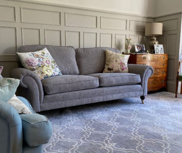 Reupholstered sofa in grey with floral cushions
