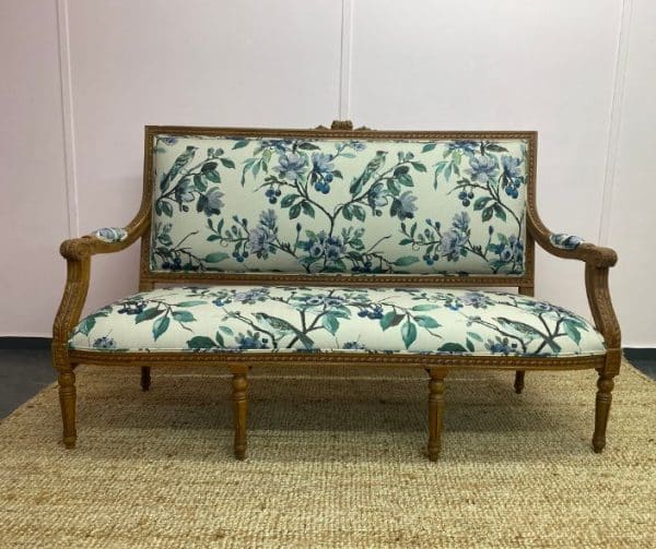 Reupholstered sofa with a pale green floral pattern with wooden arms and legs