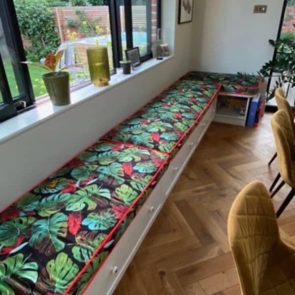 Window seat cushions seating Window seat cushions seating in a monstera fabric with red piping