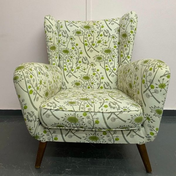 mid century chair reupholstered in a pale green, patterned fabric with wooden legs