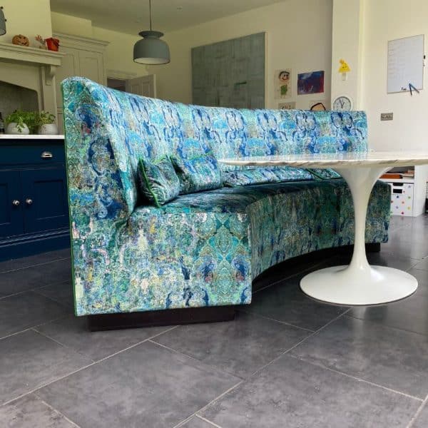 reupholstered banquette in blue and green print fabric in a kitchen with a white circular table