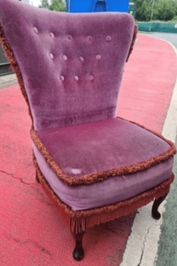 Before reupholstery: the pink velvet fringe chair sits at the recycling centre.