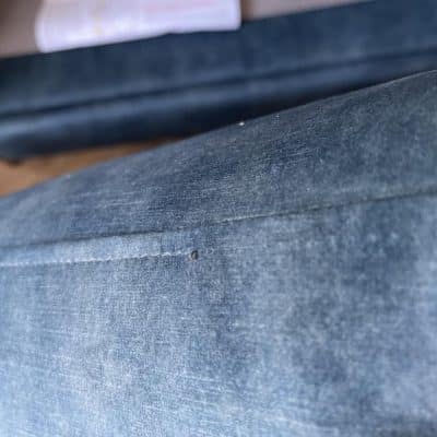 Blue velvet sofa cushion with missing stitching along the front edge.