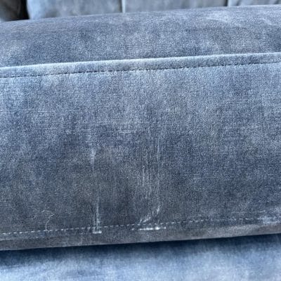 Blue velvet sofa showing abrasion marks to cushions.
