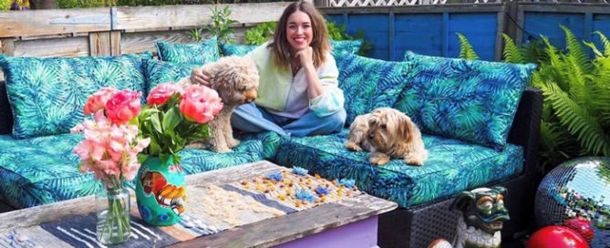 Lisa Potter Dixon sat on outdoor sofa with 2 dogs