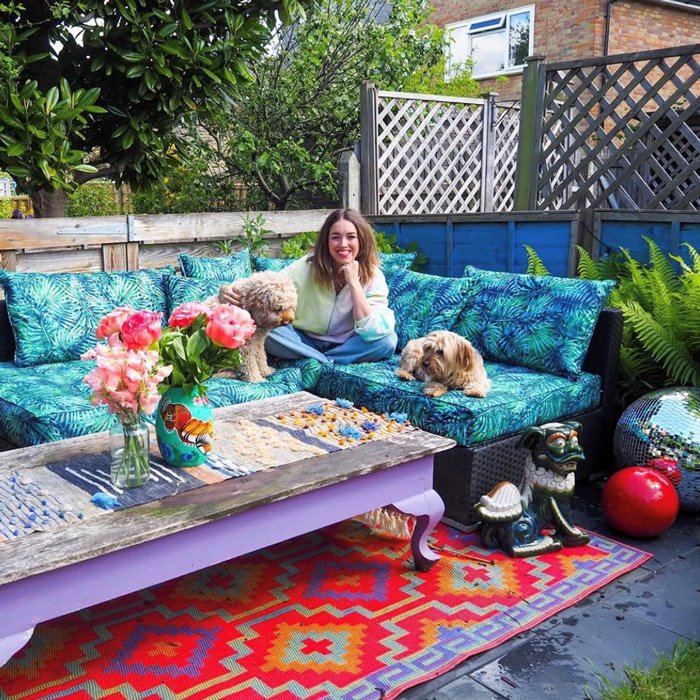 Lisa Potter Dixon sat on outdoor sofa with 2 dogs