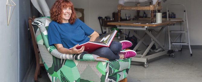 Sharon sat on a chair reupholstered in green pattern fabric in her workshop