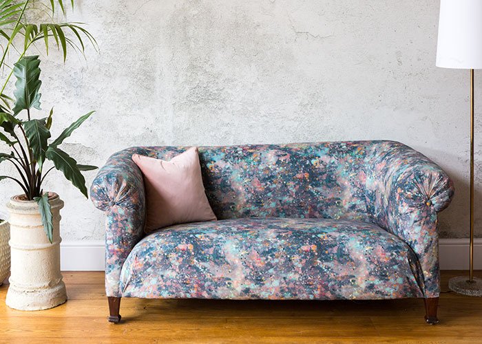 Reupholstered patterned chesterfield sofa against concrete background