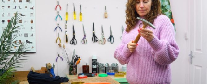 Photo of Sharon O'Connor inspecting upholstery hammer with other tools on wall in background