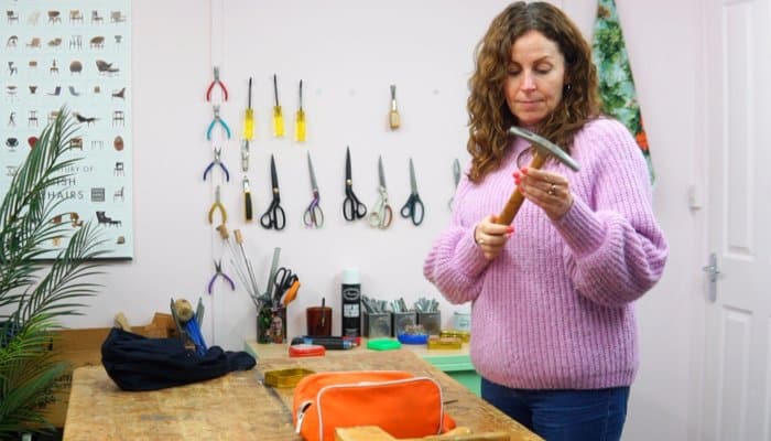 Photo of Sharon O'Connor inspecting upholstery hammer with other tools on wall in background