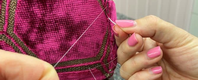 Deep pink fabric being sewn onto chair during upholstery process