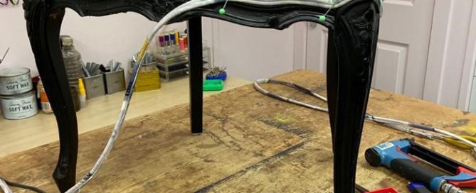 Black chair with dark wood legs having the double piping attached