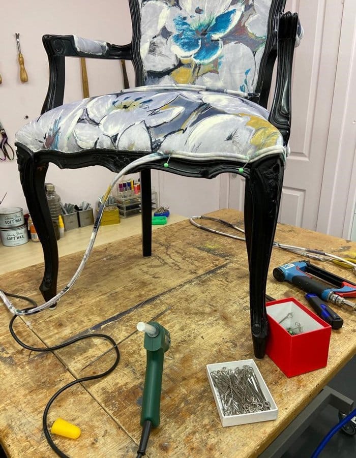 Black chair with dark wood legs having the double piping attached