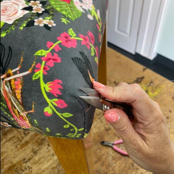 How to slip stitch - Final thread being cut for chair covered in a birds and floral fabric