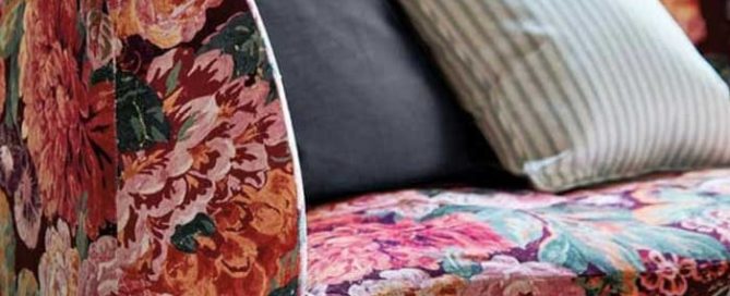 The corner of a red and pink floral upholstered sofa