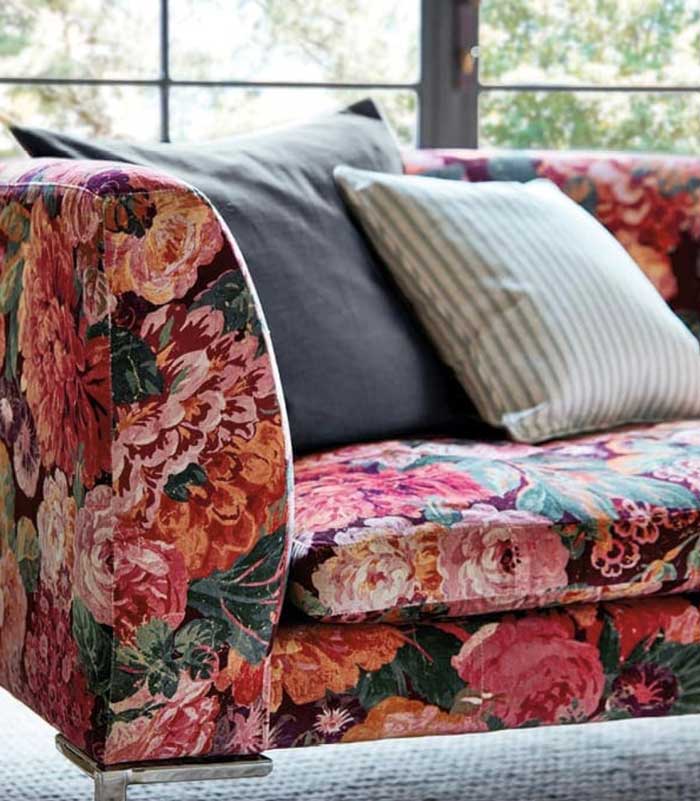 The corner of a red and pink floral upholstered sofa