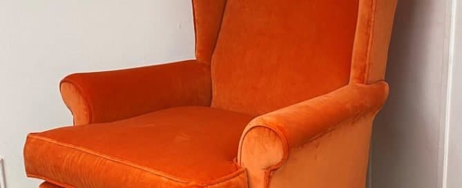 a completed reupholstered a chair in the journey of reupholstering a chair. Wing back chair covered in an orange fabric