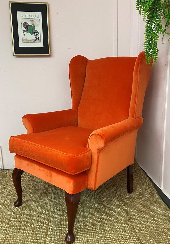 a completed reupholstered a chair in the journey of reupholstering a chair. Wing back chair covered in an orange fabric