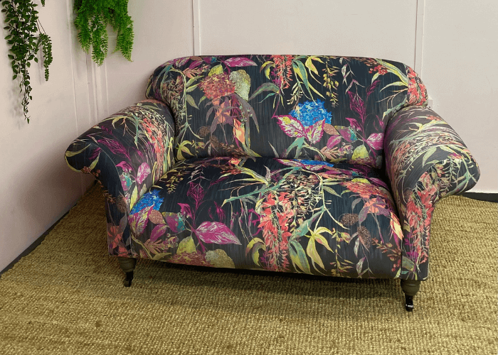 2 seater sofa upholstered in a vibrant fabric on a hessian rug