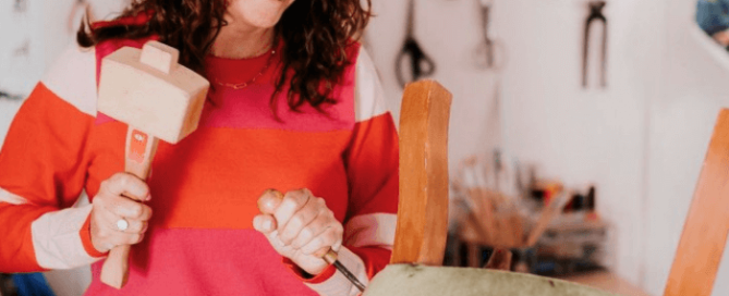 Sharon O'Connor at work reveals the best places to buy upholstery supplies. Here she is holding a mallet and chisel to remove fabric on an upturned chair
