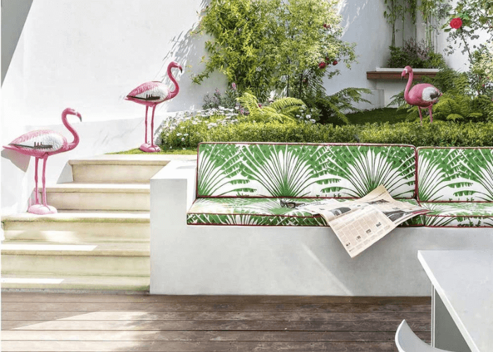 Garden seat with cushions in a green palm tree design Palma Verde by Michael Szell. Flamingos in the background