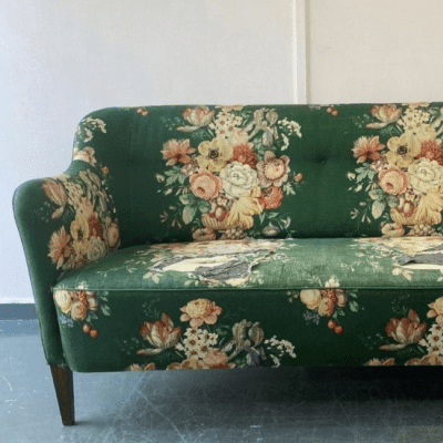 Green sofa needing upholstery in a vintage floral design