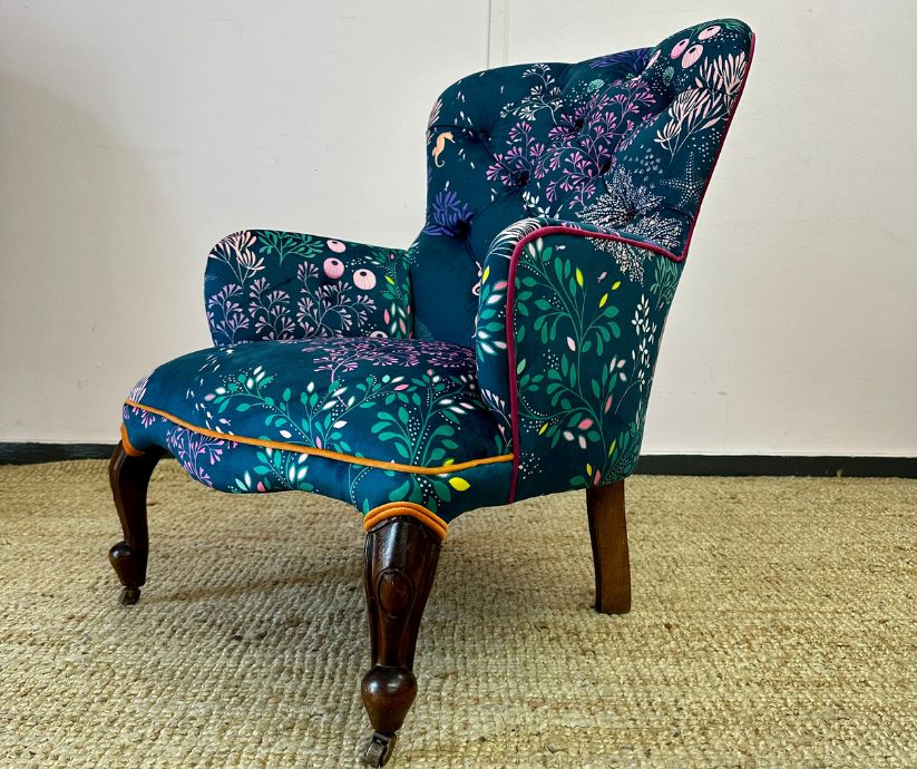 Chair covered in a dark patterned fabric with dark wooden legs