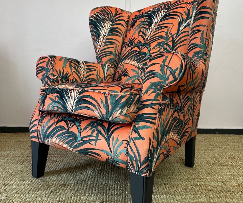reupholstered wingback chair in coral with a palm leaf print