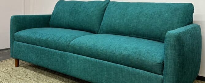 A green sofa that has been customised by an expert upholsterer