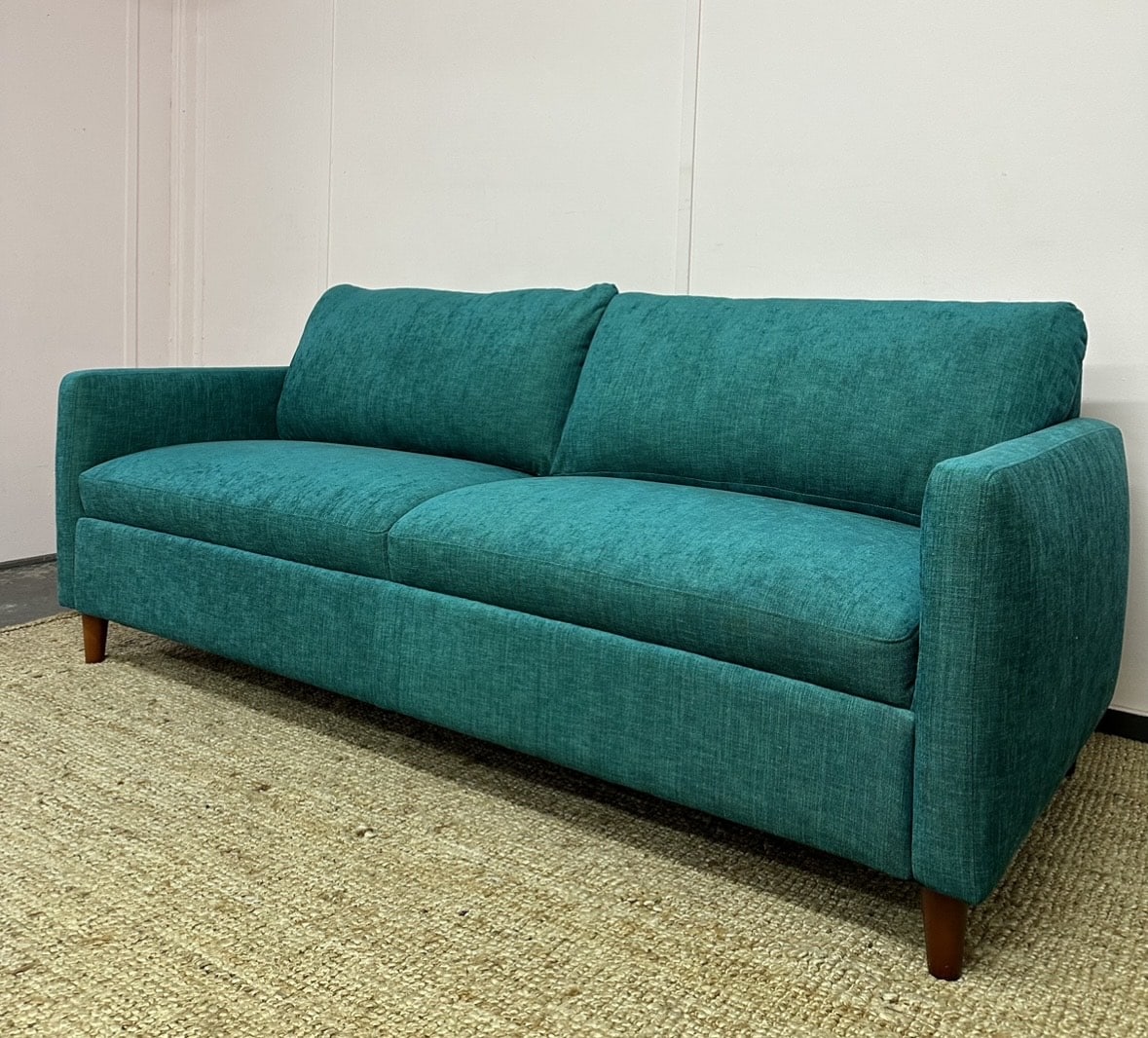 A green sofa that has been customised by an expert upholsterer